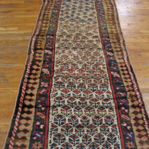 Long traditional runner with red, blue, and ivory repeating patterns resting on light brown hardwood floors.