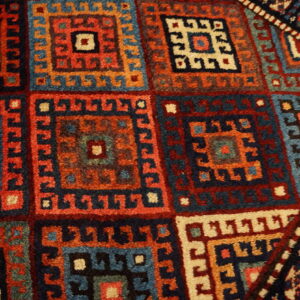 High-pile rug detail showing repeating geometric medallions in navy, rust, teal, and cream colors.