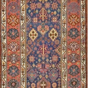 Low-pile runner featuring a dense geometric pattern on a deep blue ground framed by wide coral medallion borders.