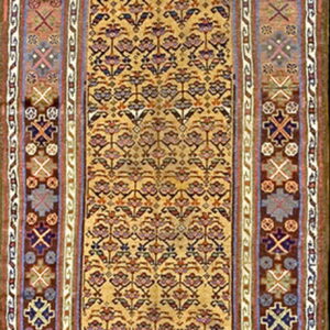 Gold runner rug displaying small repeating purple and red floral designs framed by complex geometric side borders.