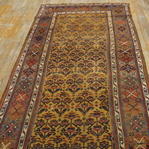 Mustard yellow runner rug with repeating floral patterns and wide geometric borders rests on plank wood flooring.