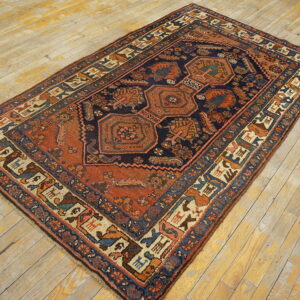 A detailed navy and terracotta geometric rug with animal figures lies on a distressed light wood floor.