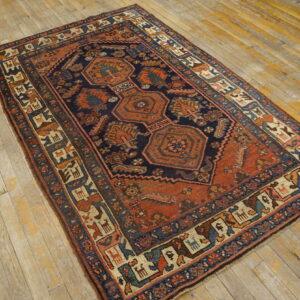 Traditional navy and terracotta rug with geometric medallions and tribal borders on distressed wood floors.