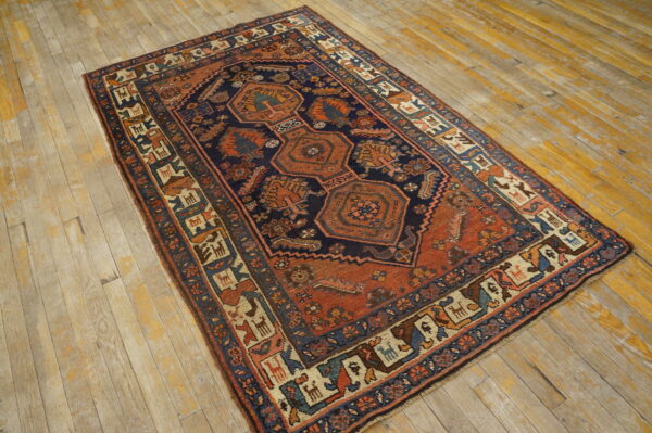 Traditional navy and terracotta rug with geometric medallions and tribal borders on distressed wood floors.