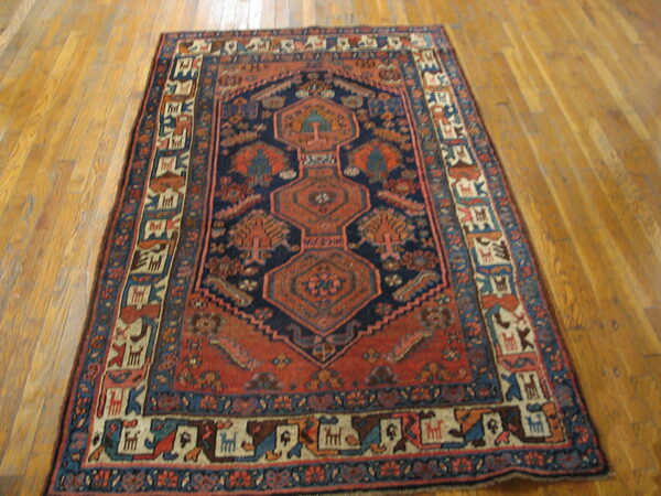 Navy and rust geometric rug featuring small animal motifs in the border, displayed on hardwood flooring.