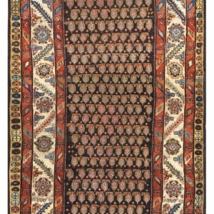 A traditional rug with a dark field, dense boteh pattern, and wide cream and rust colored borders.