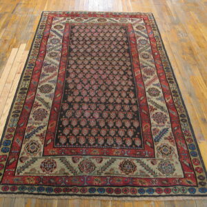 Red and black patterned rug featuring beige and blue borders, displayed across light glossy hardwood flooring.