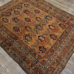 Earth-toned rug featuring geometric motifs and layered borders rests on light gray hardwood planking.