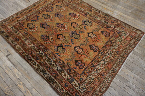 Earth-toned rug featuring geometric motifs and layered borders rests on light gray hardwood planking.