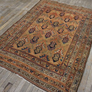 Orange and rust geometric rug with blue accents rests on distressed gray wood plank flooring.