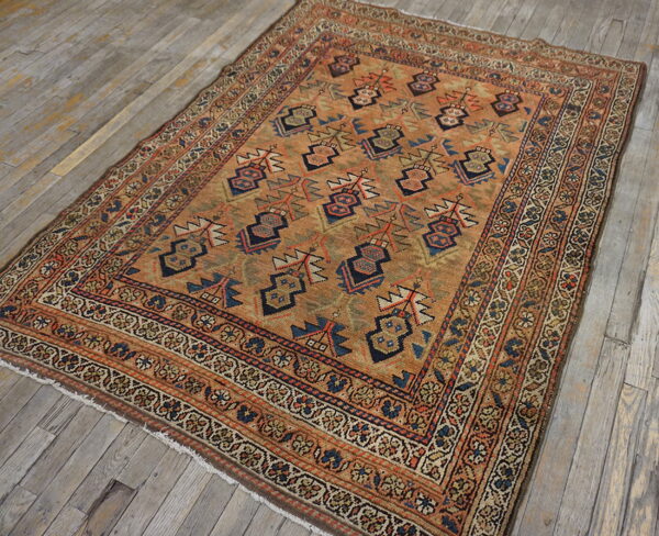 Orange and rust geometric rug with blue accents rests on distressed gray wood plank flooring.