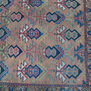Low-pile rug with a detailed geometric pattern in terracotta, blue, navy, and olive green.