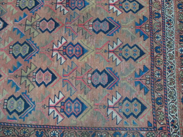 Low-pile rug with a detailed geometric pattern in terracotta, blue, navy, and olive green.