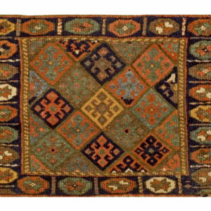 Square rug with a central diamond pattern in rust, green, brown, and navy, framed by an oval motif border.