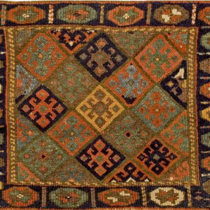 Coarse, low-pile rug featuring complex diamond and medallion patterns in olive green, navy, and deep orange.