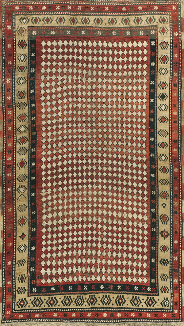 Red and beige rug featuring an all-over small diamond pattern and multi-layered geometric borders.