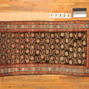 Dark brown runner rug featuring intricate red, blue, and beige geometric patterns on wood flooring.