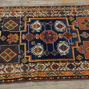 Colorful geometric runner rug with complex red, blue, and gold tribal patterns on wood planks.
