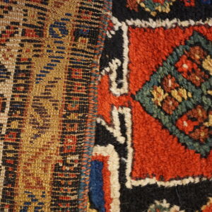 Close-up showing flat-woven tan geometric pattern next to a shaggy red and black piled design.