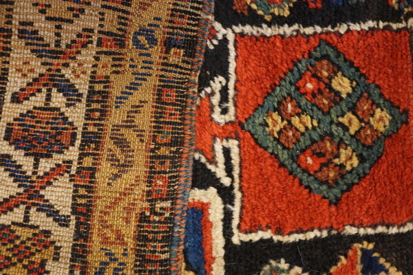 Close-up showing flat-woven tan geometric pattern next to a shaggy red and black piled design.