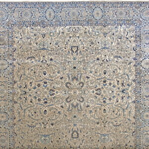 A finely detailed rug with a beige field and complex light and dark blue floral designs and wide borders.