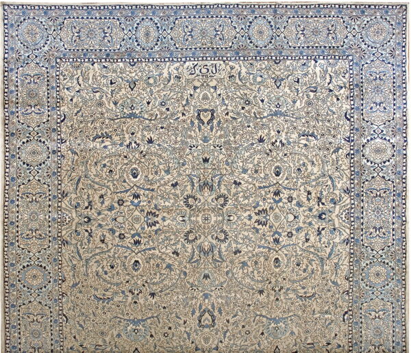A finely detailed rug with a beige field and complex light and dark blue floral designs and wide borders.