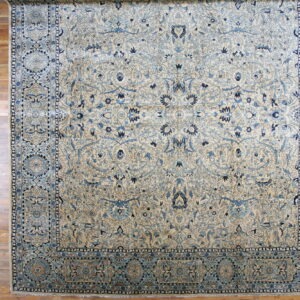 Traditional cream rug with intricate light and deep blue floral designs flat on warm wood flooring.
