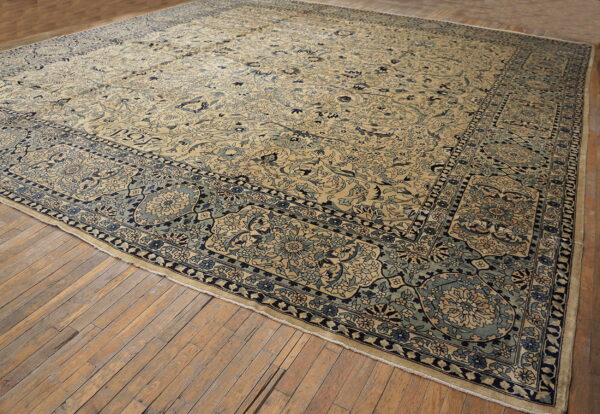 Large beige rug with dense blue floral patterns and medallions laid on light hardwood floors.