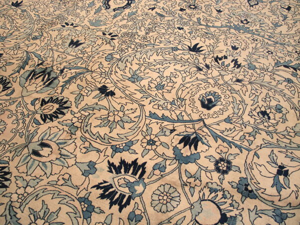 Low-pile rug detailed with intricate blue floral and vine motifs on a light beige background.