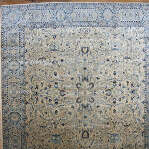 A large cream rug with intricate blue floral borders and vines rests on wood planks.