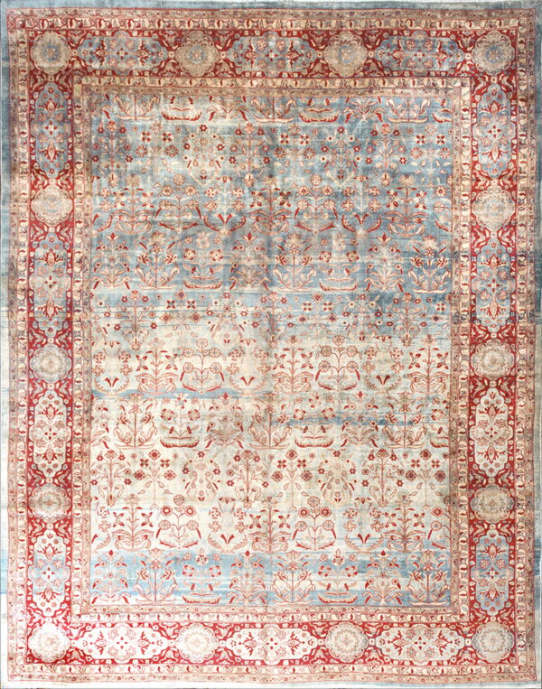 Ornate floral rug with striated blue and cream field, framed by complex red and beige borders.