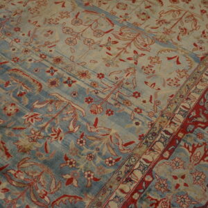 Ornate floral rug with alternating faded blue and cream stripes, featuring red and tan details.