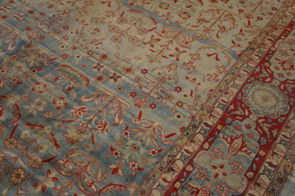 Ornate floral rug with alternating faded blue and cream stripes, featuring red and tan details.