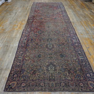 A distressed floral runner in navy, beige, and rose lies on worn, wide-plank wood flooring.