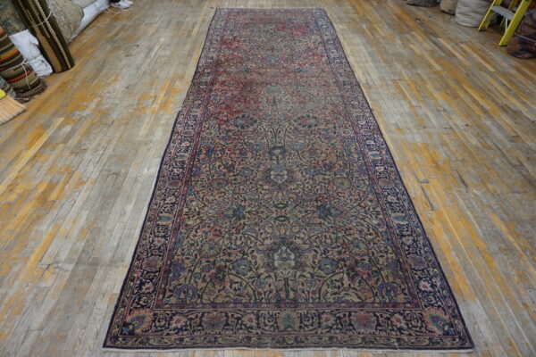 A distressed floral runner in navy, beige, and rose lies on worn, wide-plank wood flooring.