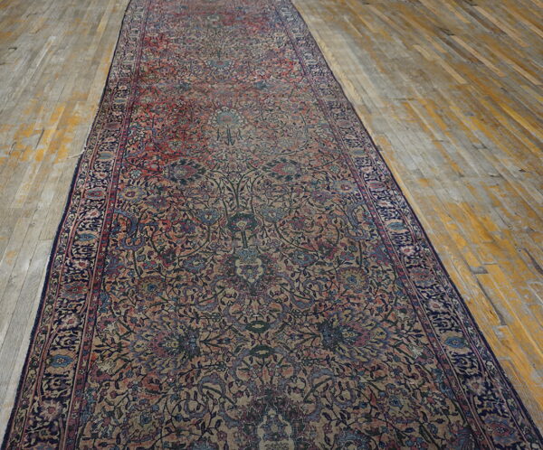 A long, ornate runner with complex red, blue, and tan floral designs covers weathered wooden floorboards.