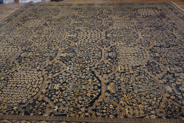 Navy rug with dense beige, gold, and blue floral patterns covers a light wood floor.