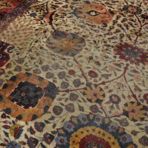 Close-up of a detailed floral rug in cream, red, blue, and gold with a visible patterned border section.