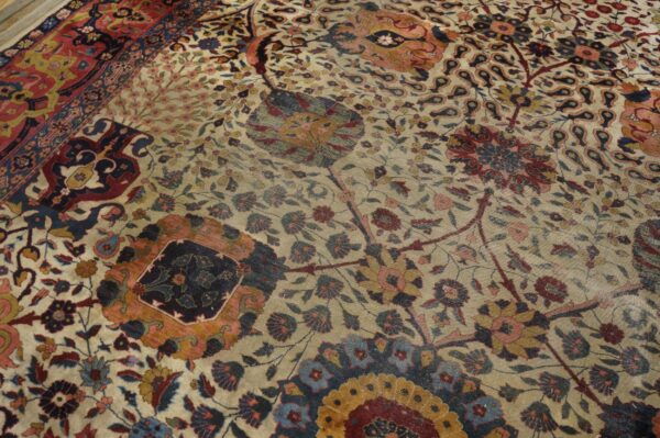 Close-up of a detailed floral rug in cream, red, blue, and gold with a visible patterned border section.