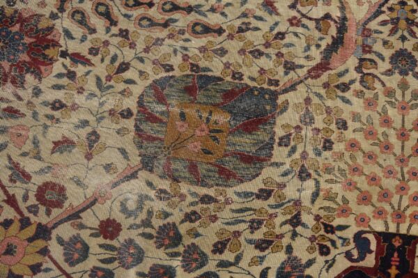 Intricate floral rug pattern on a beige ground featuring colors of deep red, navy, pink, and gold.