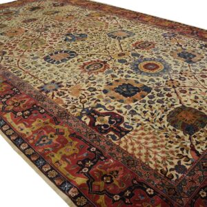 A large, low-pile rug with a cream field, ornate floral motifs, and a detailed red border.