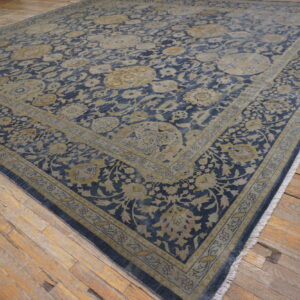 Low-pile rug in blue and tan floral medallion pattern covering rustic wood planks.