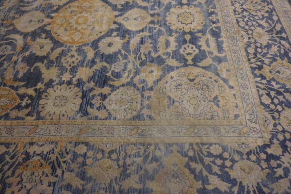 Ornate gold and tan floral patterns overlay a striated navy blue background, highlighting the rug's border design.