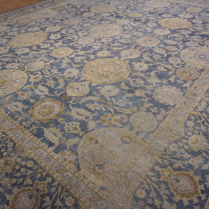 Large blue and beige rug with traditional medallion patterns on a wooden floor.