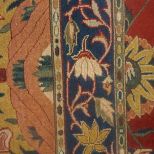 Intricate rug detail showing a blue floral border next to salmon and red patterned fields.