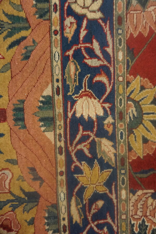 Intricate rug detail showing a blue floral border next to salmon and red patterned fields.