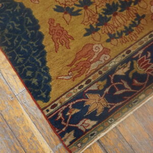 Gold, blue, and rust patterned rug detail resting on heavily distressed light wood flooring.