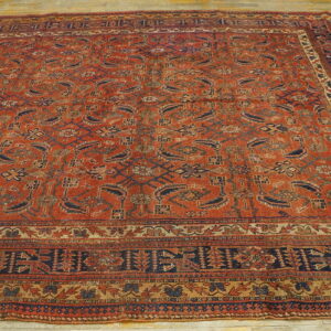 Low-pile rust red area rug featuring dense geometric and floral patterns sits on a wooden floor.
