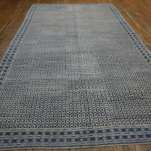 A large blue and beige patterned rug with a detailed border rests on rustic wood floors.