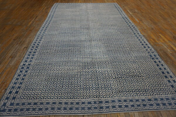 A large blue and beige patterned rug with a detailed border rests on rustic wood floors.
